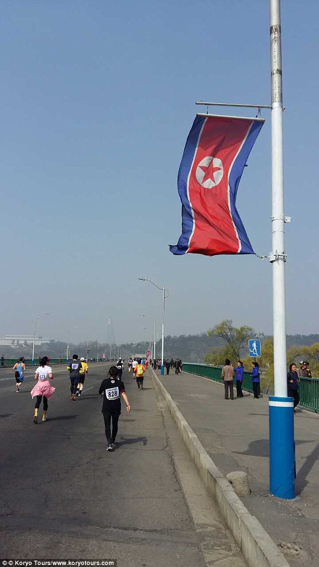 Runners make their way past a North Korean flag in the marathon