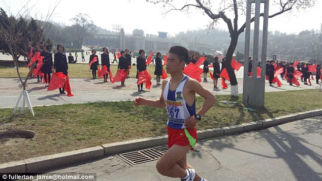 A runner of the Pyongyang marathon runs past girls who cheered him on with red flags