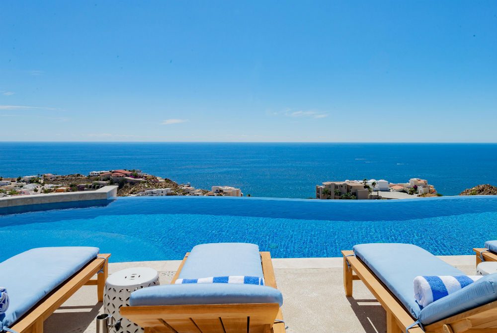 chaise lounges overlooking infinity pool and blue ocean in Cabo San Lucas Mexico